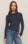Woman wearing a dark blue ribbed sweater and jeans on a beige background