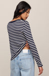 Woman wearing a navy and white striped long-sleeve top and light blue jeans on a beige background
