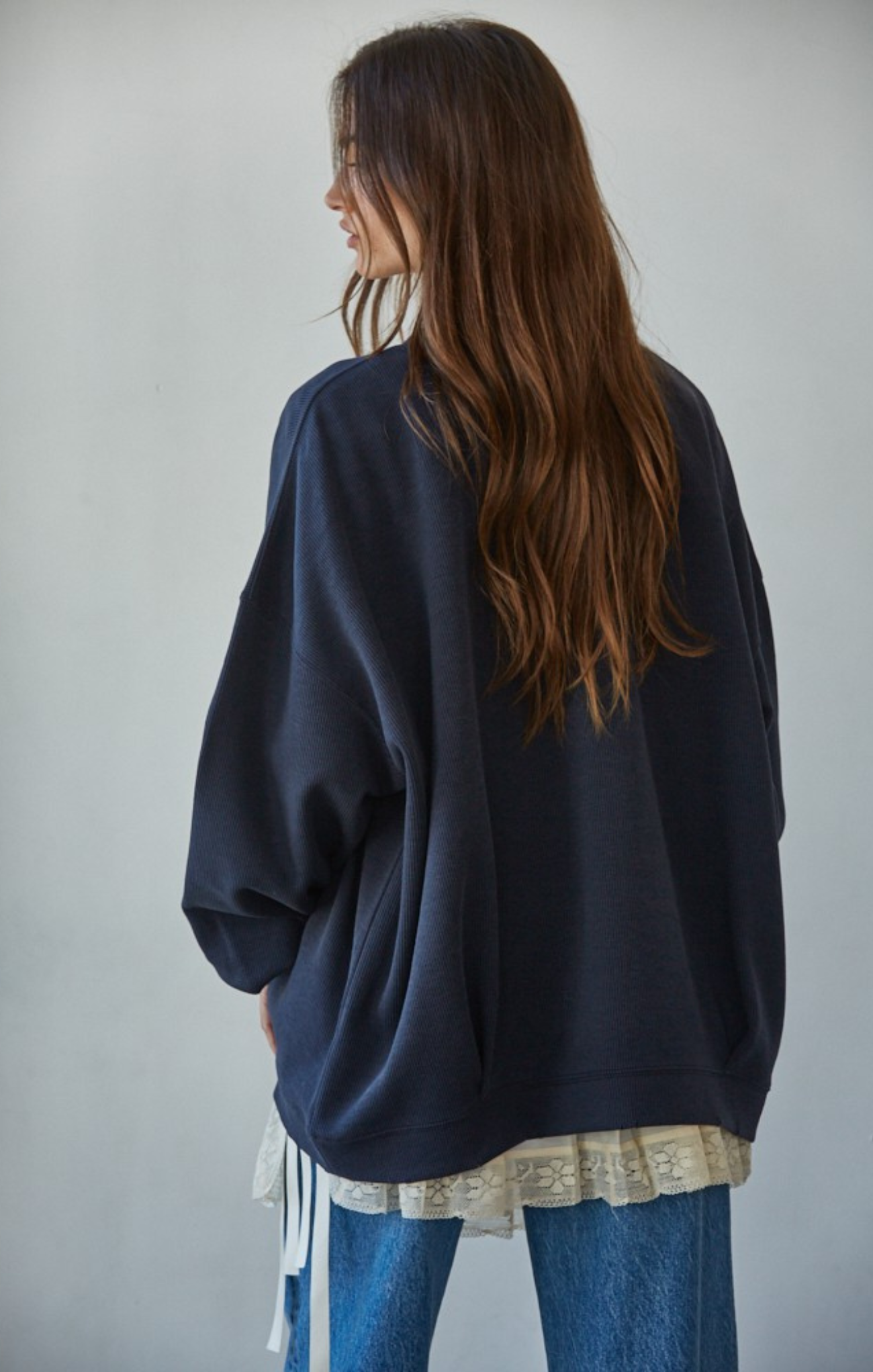 Person wearing a dark blue oversized sweater with a plain background