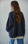 Person wearing a dark blue oversized sweater with a plain background