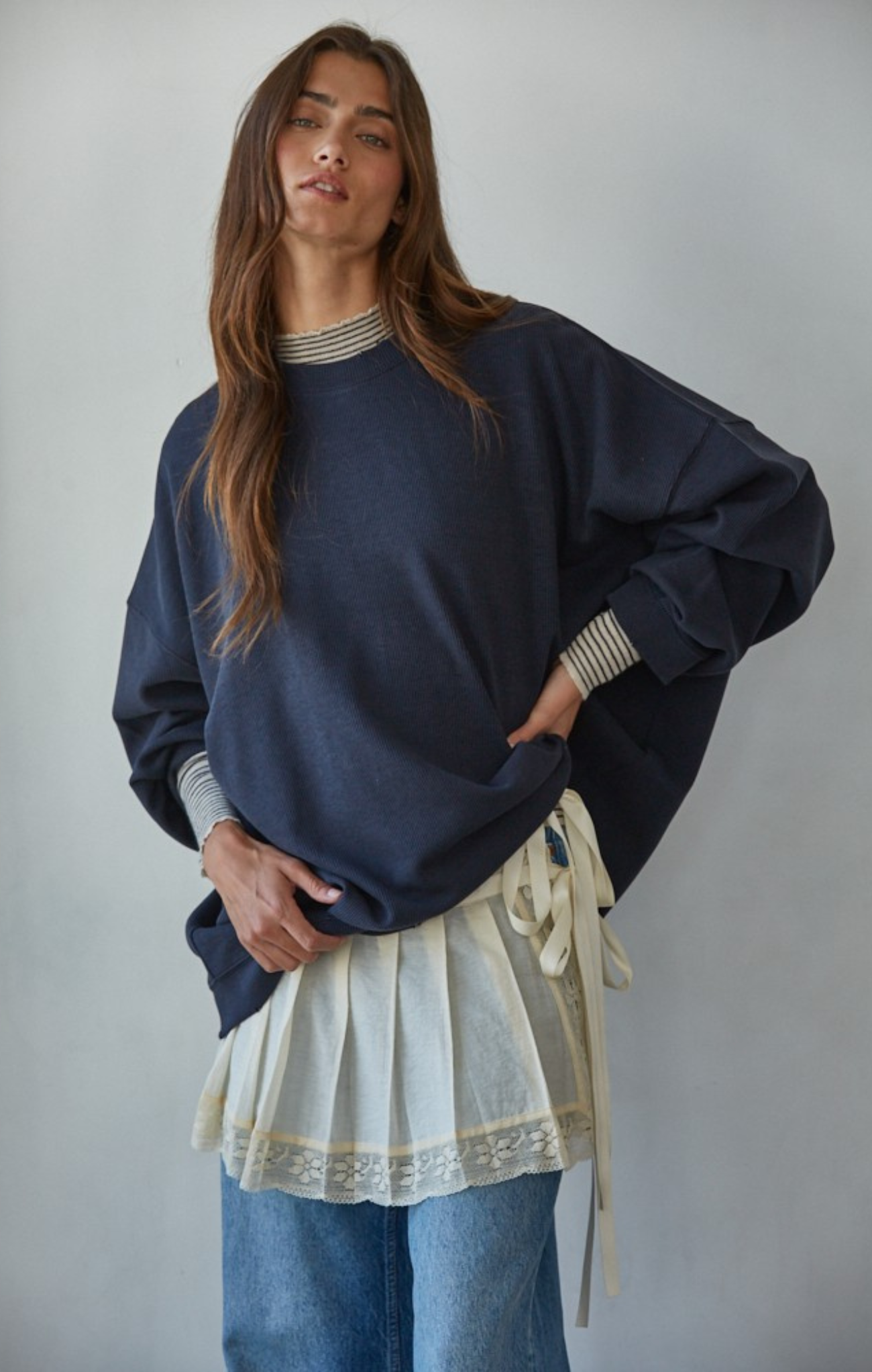 Woman wearing a navy sweater over a white apron with a plain background