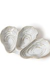 Three oyster-shaped ceramic dishes on a white background