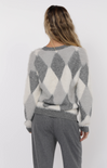 Person wearing a gray and white patterned sweater with matching pants on a white background