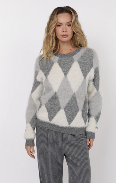 Woman wearing a gray and white argyle sweater with matching pants on a white background