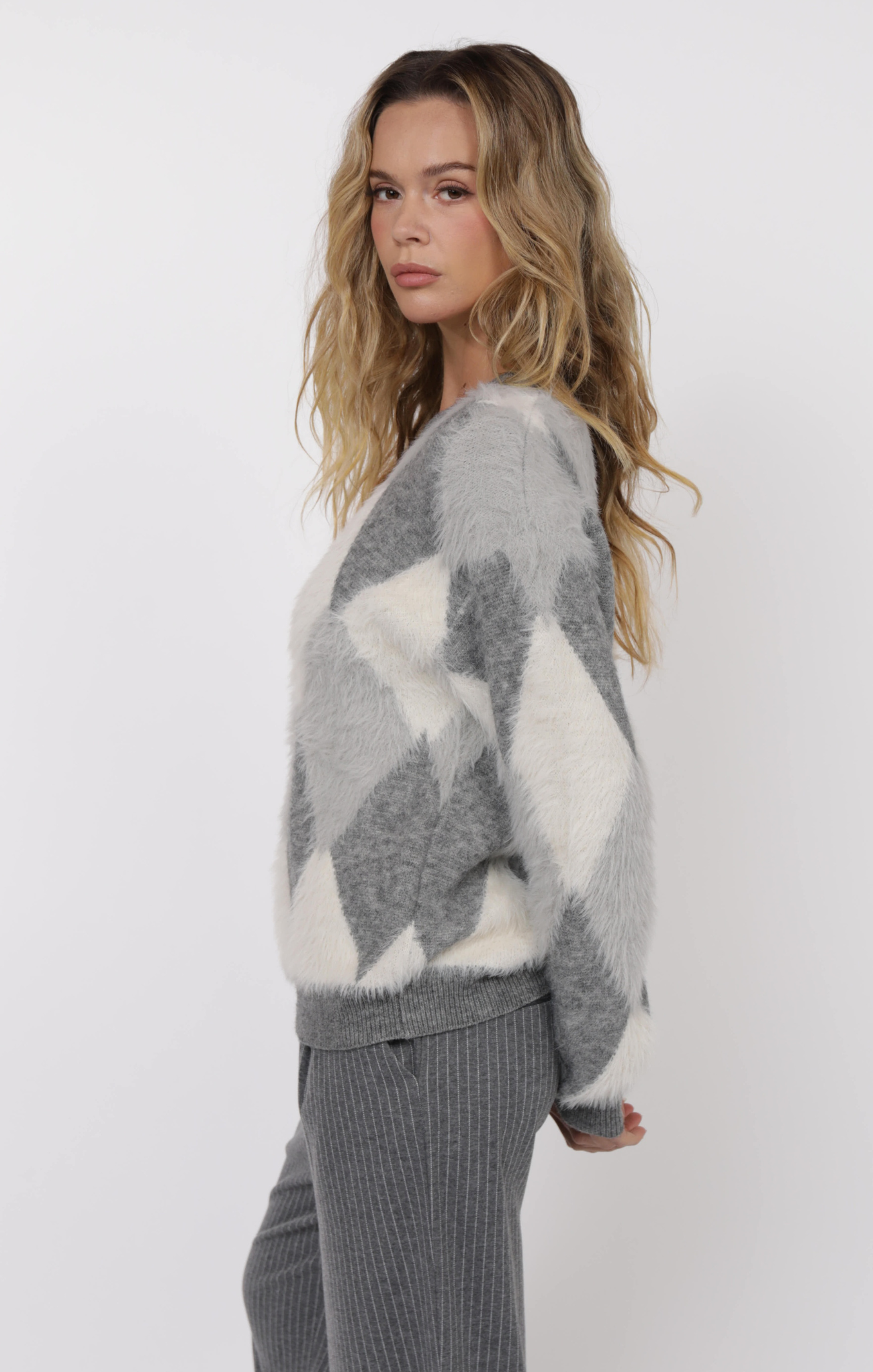 Woman wearing a gray and white patterned sweater on a white background