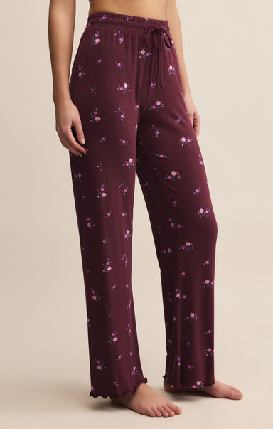 Maroon pajama pants with floral pattern worn by a person on a beige background