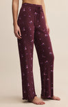 Maroon pajama pants with floral pattern worn by a person on a beige background