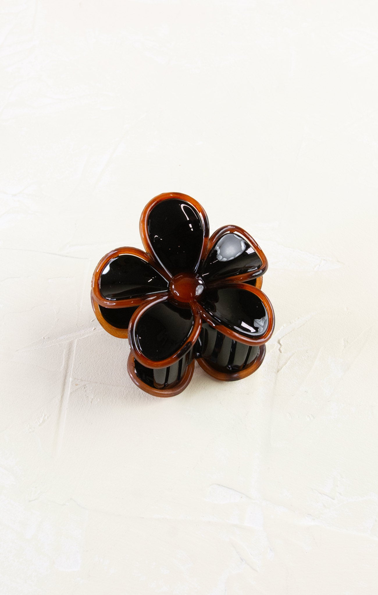 Flower-shaped hair clip with black and brown colors on a white background