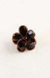 Flower-shaped hair clip with black and brown colors on a white background