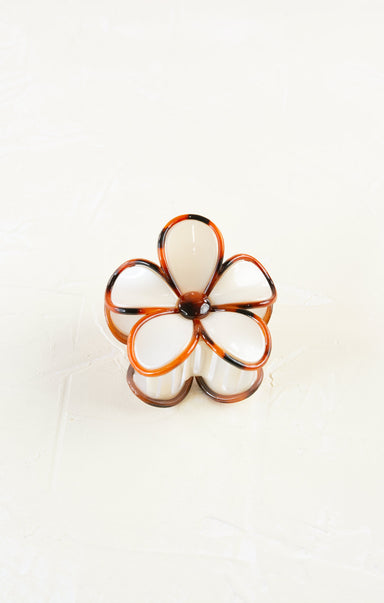 Flower-shaped ring with white and orange design on a white background