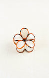 Flower-shaped ring with white and orange design on a white background