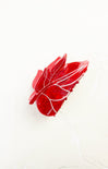 Red leaf-shaped glass ornament on a white background