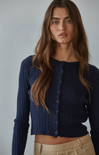 Woman wearing a navy blue knitted cardigan against a gray background