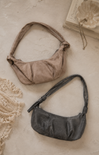 Two handbags, one brown and one black, on a textured surface with lace and books in the background.