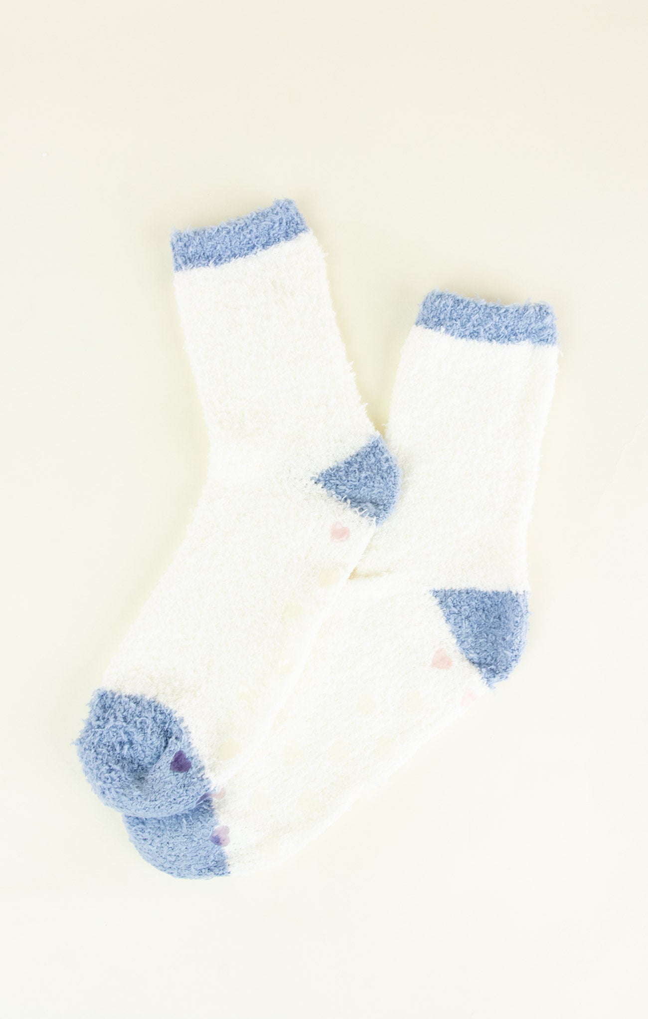 Pair of white socks with blue fuzzy accents on a light background