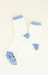 Pair of white socks with blue fuzzy accents on a light background