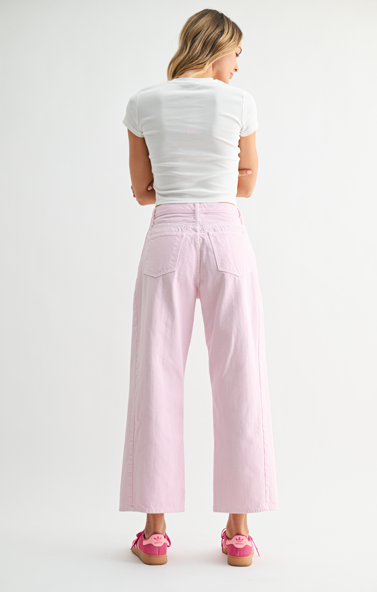 Woman wearing a white top and pink pants on a white background