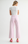 Woman wearing a white top and pink pants on a white background