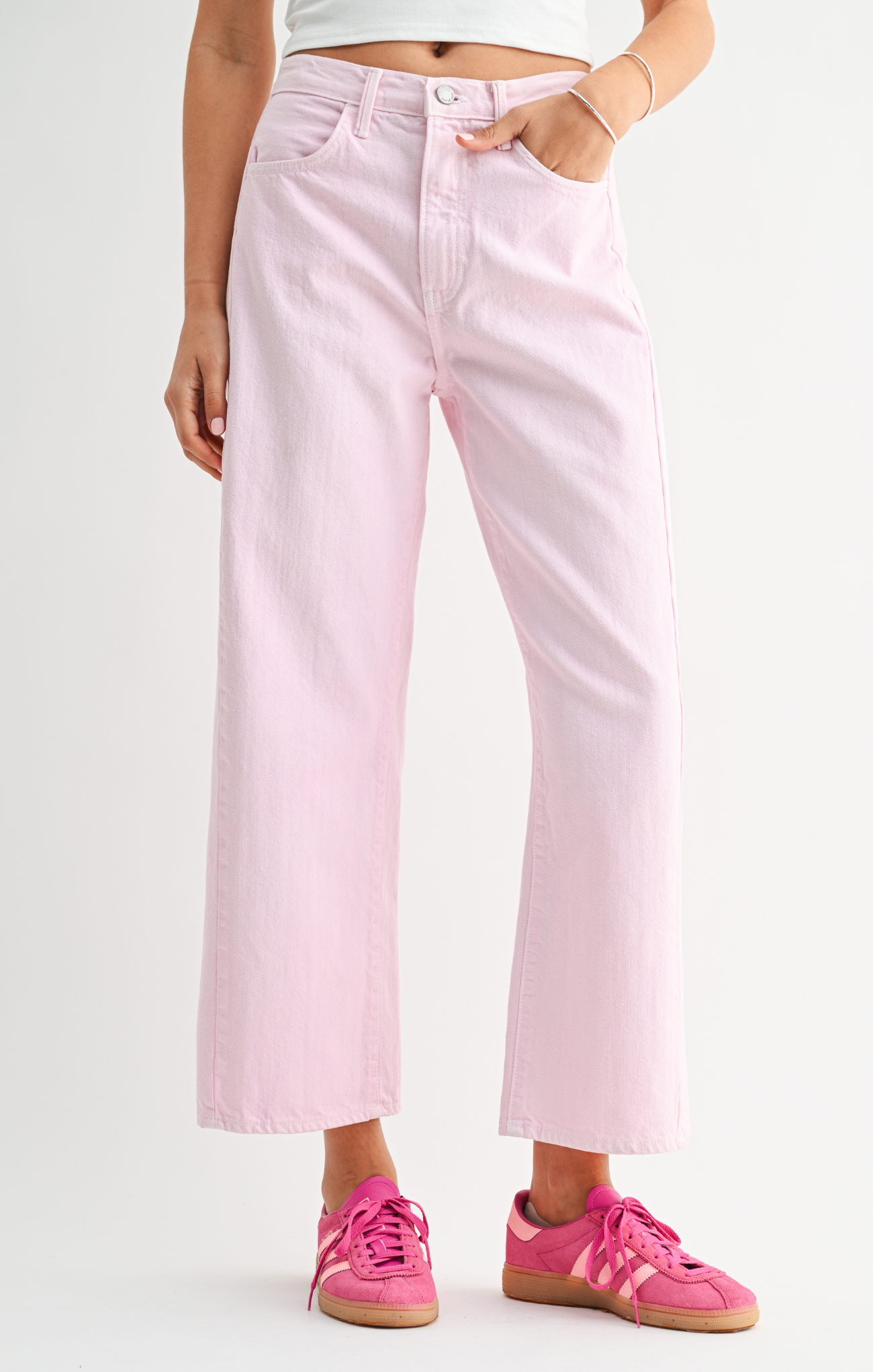 Person wearing light pink jeans and pink sneakers on a white background