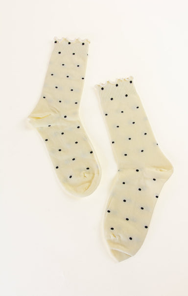 Pair of cream-colored socks with black polka dots on a white background