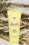 Yellow sunscreen lotion tube with 'bask' branding on a textured beige background