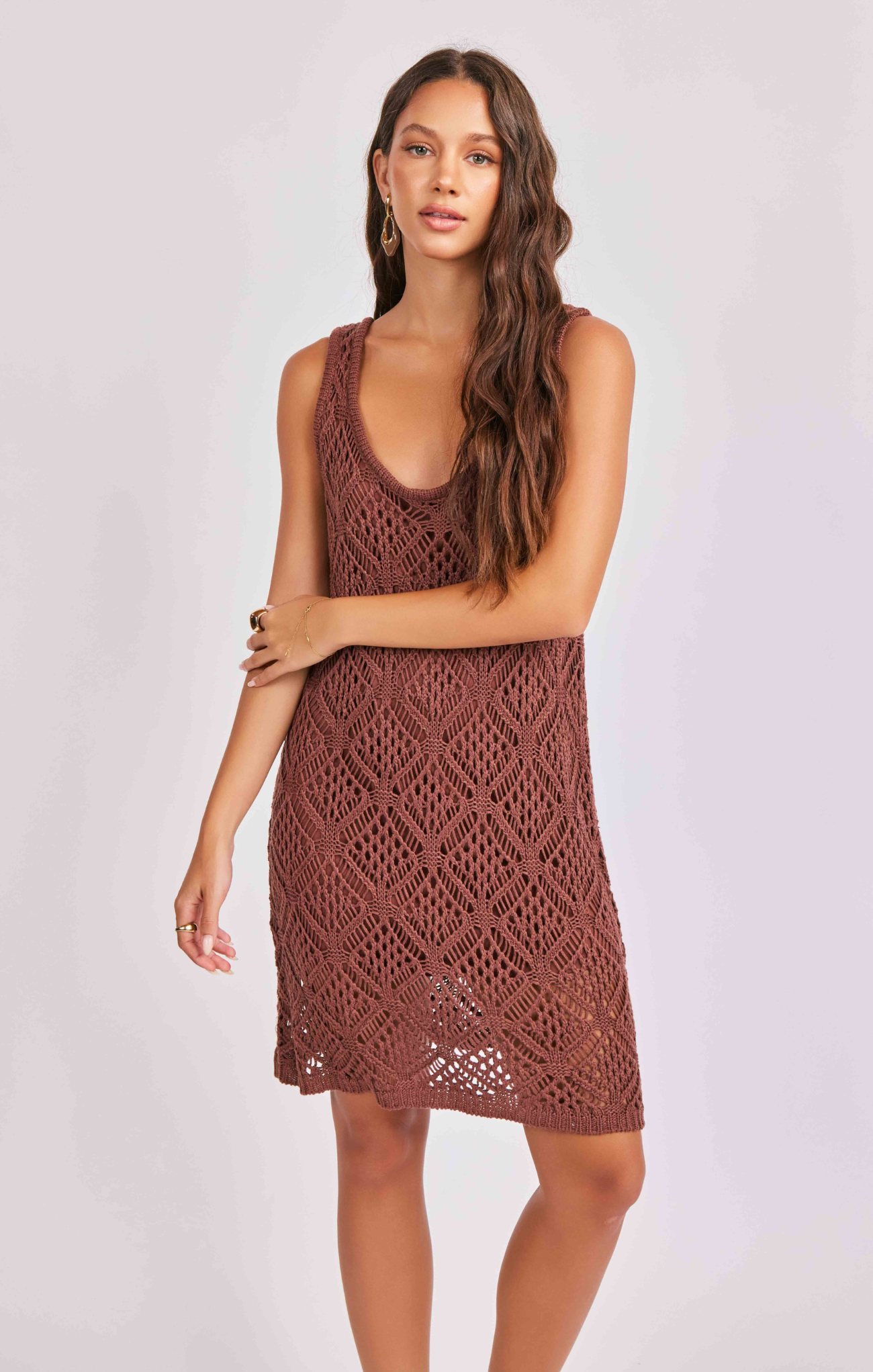 Woman wearing a brown crochet dress against a white background