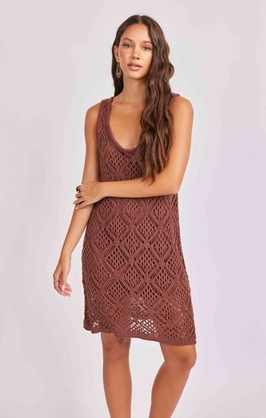Woman wearing a brown crochet dress against a white background