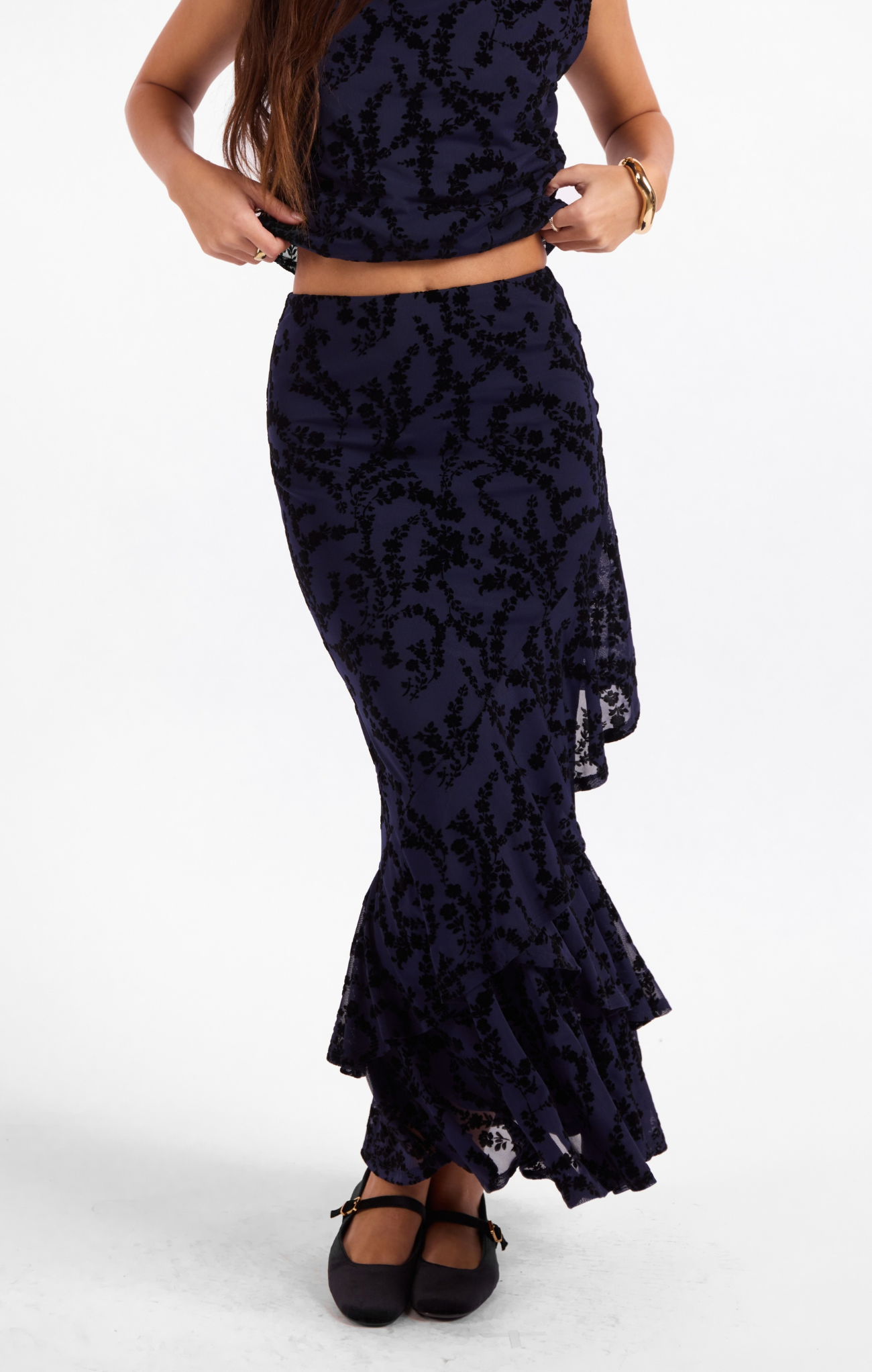 Person wearing a black lace top and matching skirt on a white background