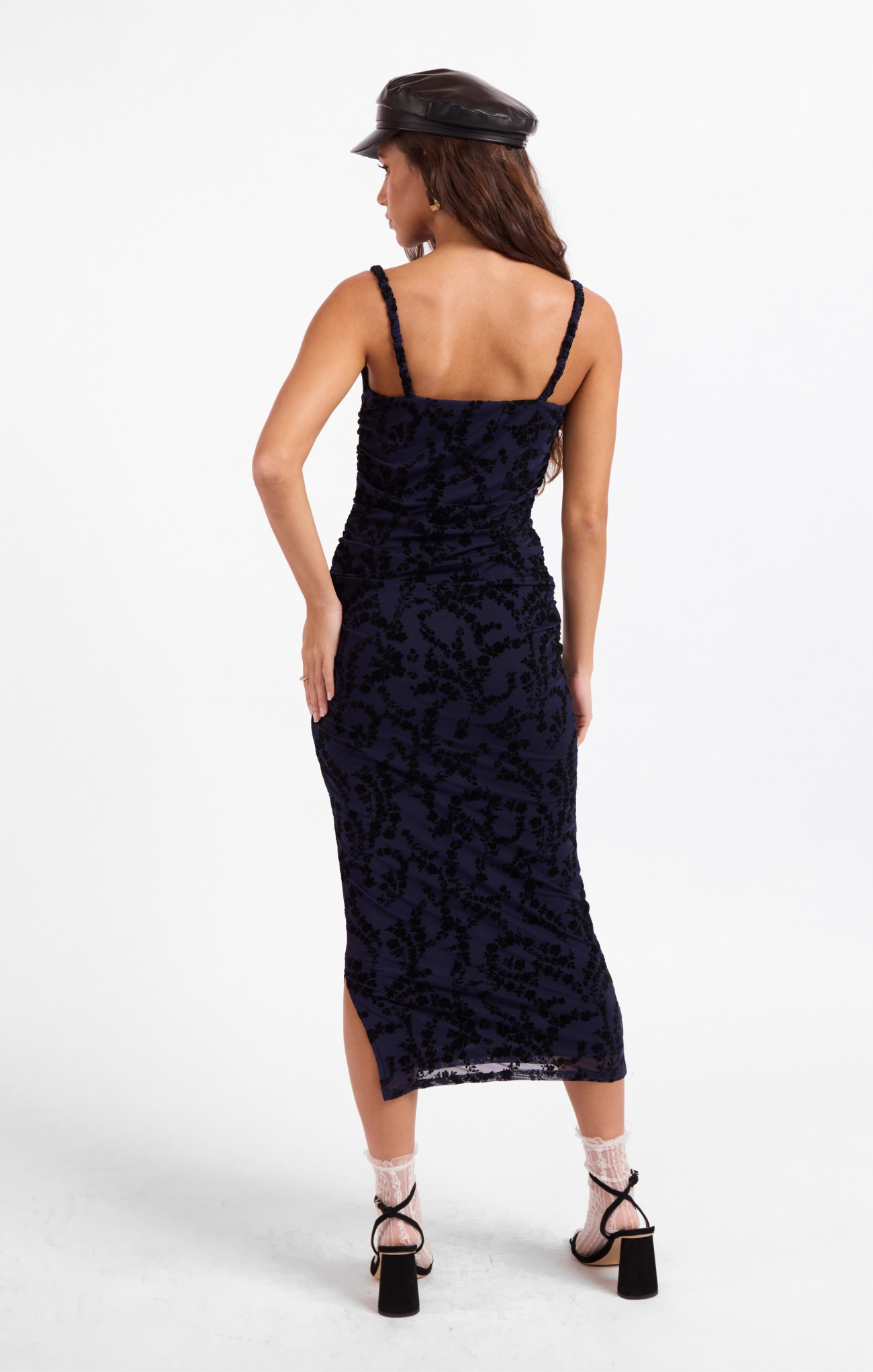 Woman wearing a black lace dress with thin straps on a white background