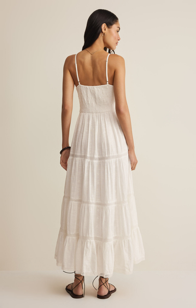 Woman wearing a white dress with thin straps on a beige background