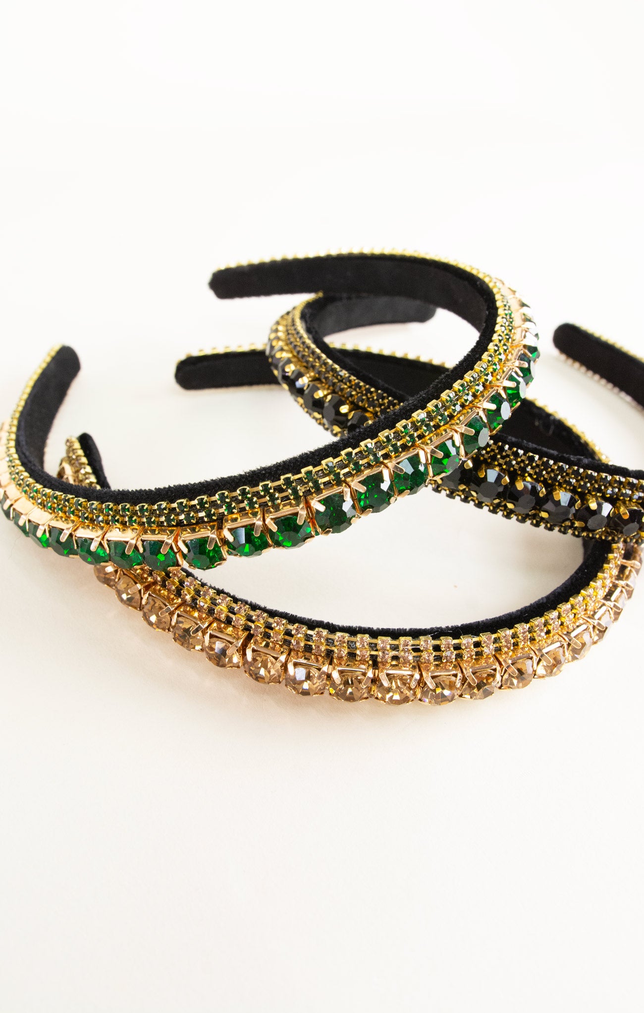 Three decorative headbands with green and gold embellishments on a white background