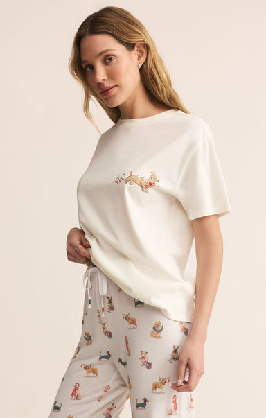 Woman wearing a white t-shirt with embroidery and patterned pants on a beige background