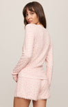 Woman wearing a pink lace outfit on a plain background