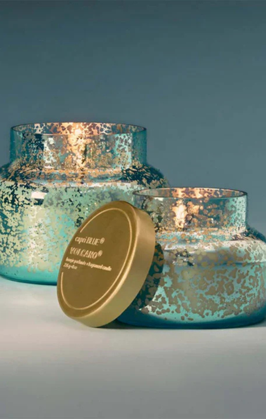 Decorative candles with metallic finish and gold lid on a gradient background