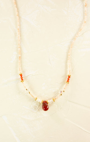 Necklace with red stone and pearls on a beige background
