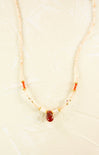 Necklace with red stone and pearls on a beige background