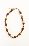 Necklace with brown beads and gold accents on a white background