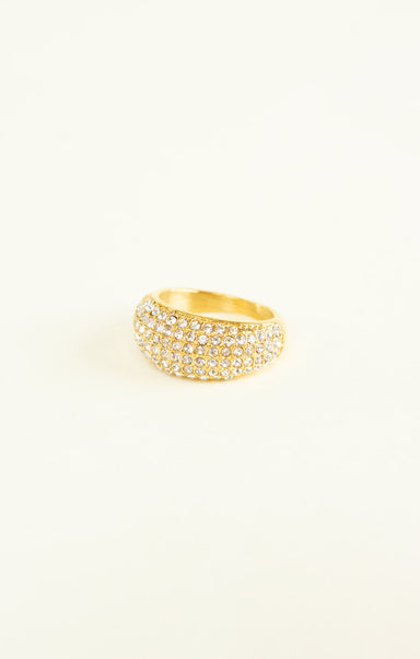 Gold ring with embedded stones on a light beige background
