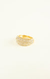 Gold ring with embedded stones on a light beige background
