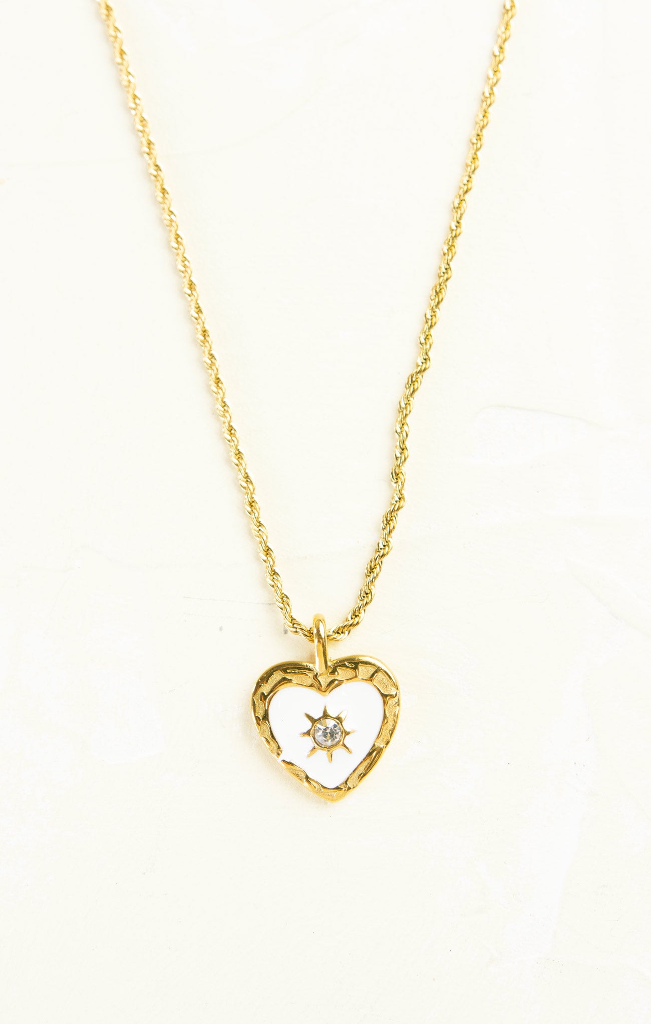 Gold heart-shaped necklace with a diamond on a white background