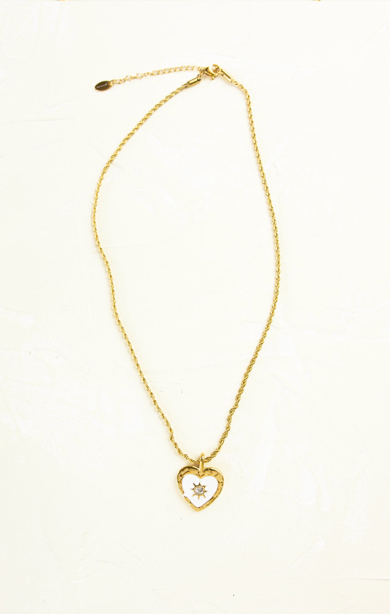 Gold necklace with a heart-shaped pendant on a white background
