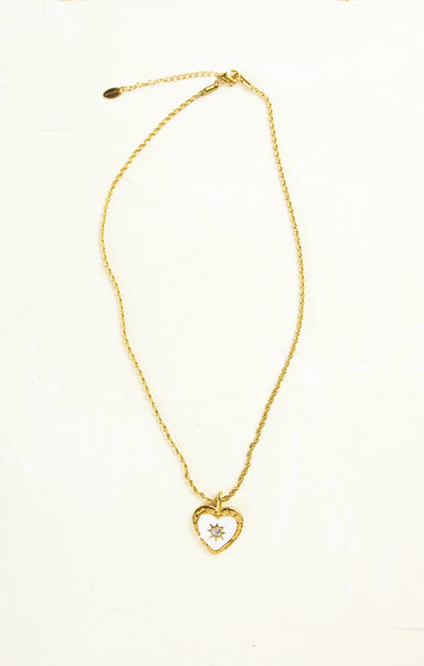 Gold necklace with a heart-shaped pendant on a white background