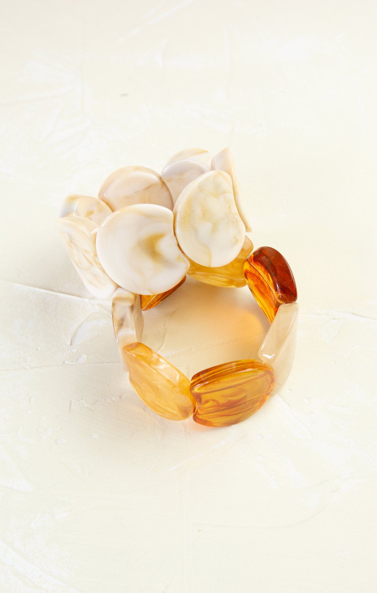 Set of three amber-colored bracelets on a white background