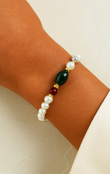 Bracelet with pearls and colored beads on a wrist against a neutral background