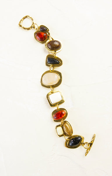 Gold bracelet with multicolored stones on a white background