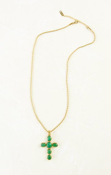 Gold necklace with a green cross pendant on a white background