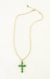 Gold necklace with a green cross pendant on a white background