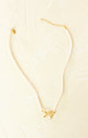 Gold necklace with a small pendant on a beige background