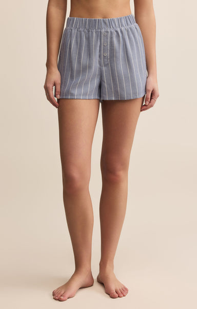 Person wearing blue striped shorts on a beige background