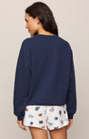Woman wearing a navy blue sweatshirt and patterned shorts on a beige background
